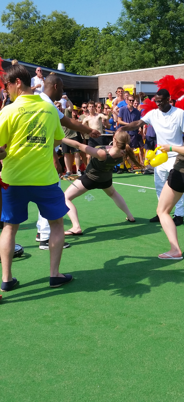 Gasten doen mee aan limbo tijdens een buitenfeest