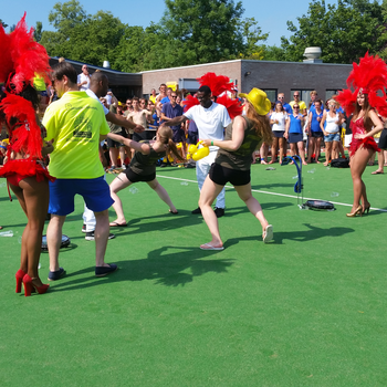 Gasten doen mee aan limbo tijdens een buitenfeest
